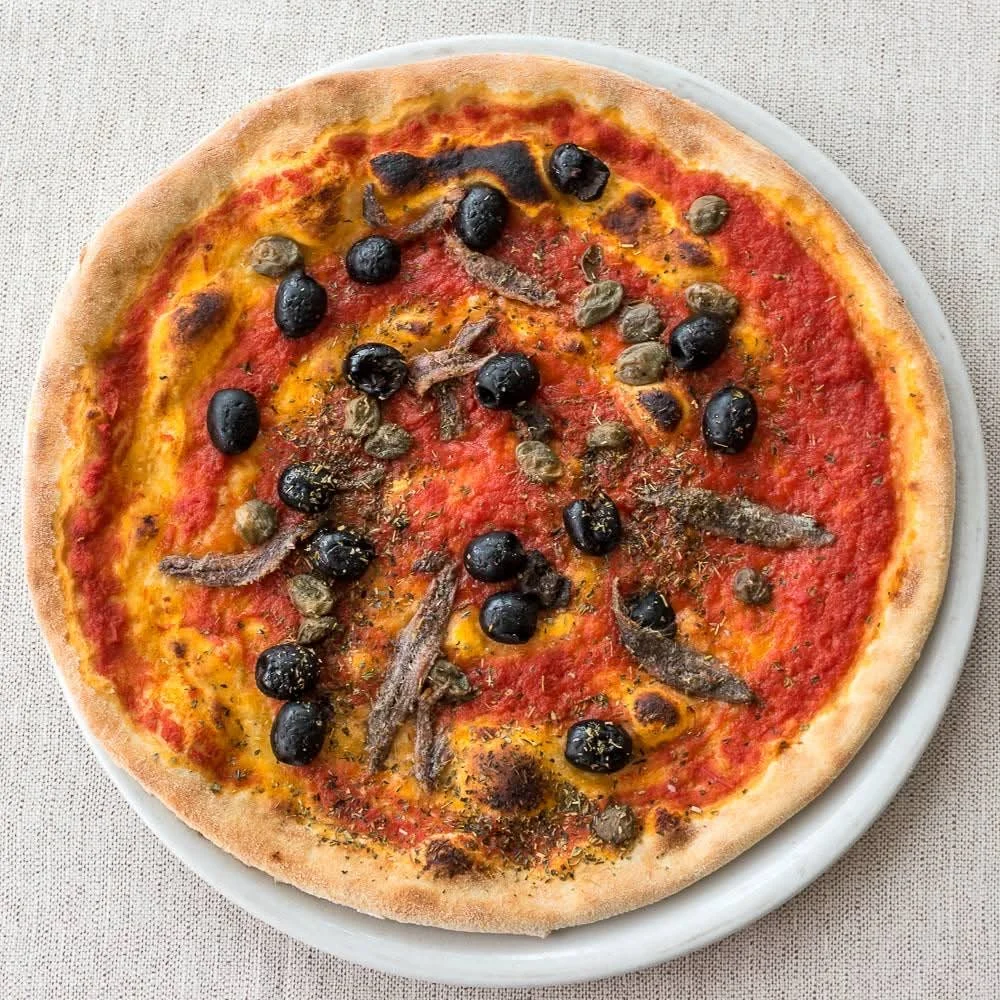 Pizza con acciughe, olive e origano